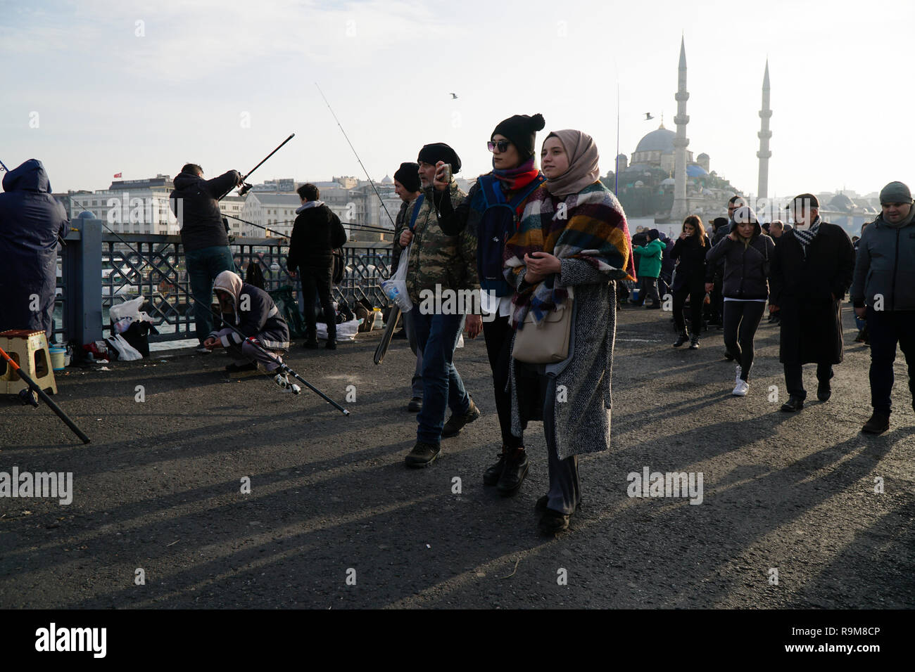 Istanbul, Turchia - 22 Dicembre 2018 : due giovani donne turche stanno camminando sul Ponte Galata. Uno di essi è tenuto selfie.altre persone sono la pesca Foto Stock