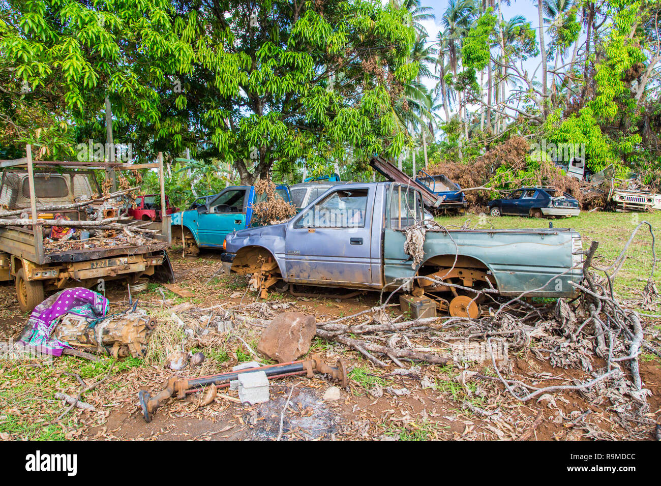 Automotive, cimitero cimitero auto cantiere, auto abbandonate junkyard sotto le palme in una remota isola di uvea, Wallis e Futuna. Problemi ecologici. Foto Stock
