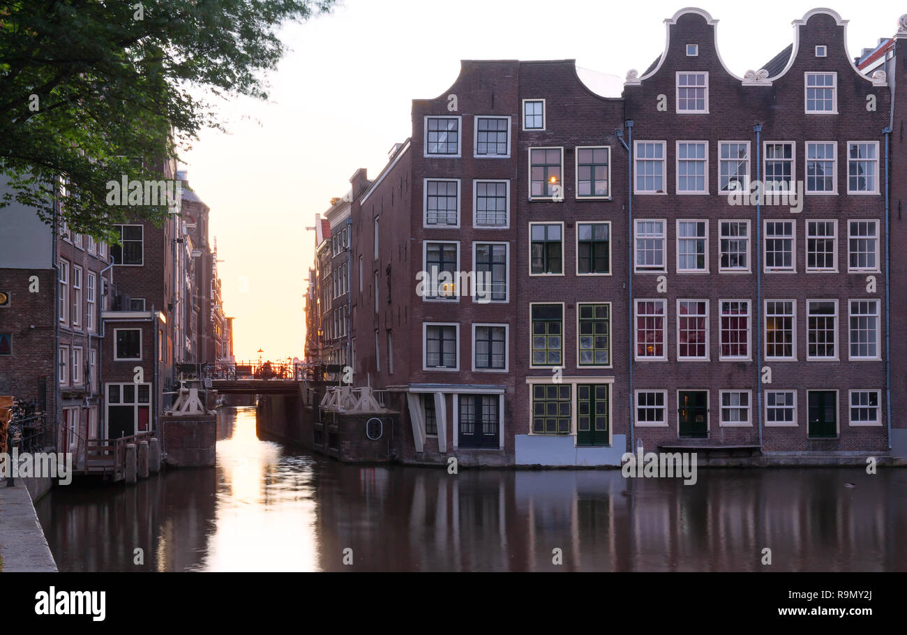 Tramonto riflesso nell'acqua del canale di Amsterdam contro lo sfondo di belle case. Foto Stock