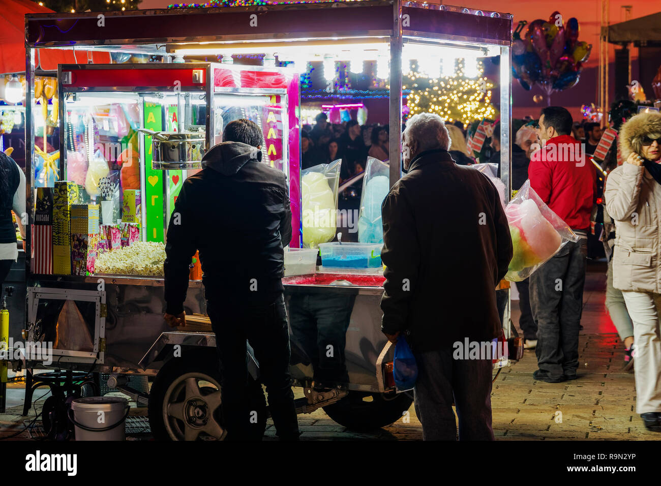 Greek street produttore presso Piazza Aristotelous, Salonicco. Vista serale della folla e illuminati rimorchio vendita caramella di cotone, castagne o pop-corn. Foto Stock