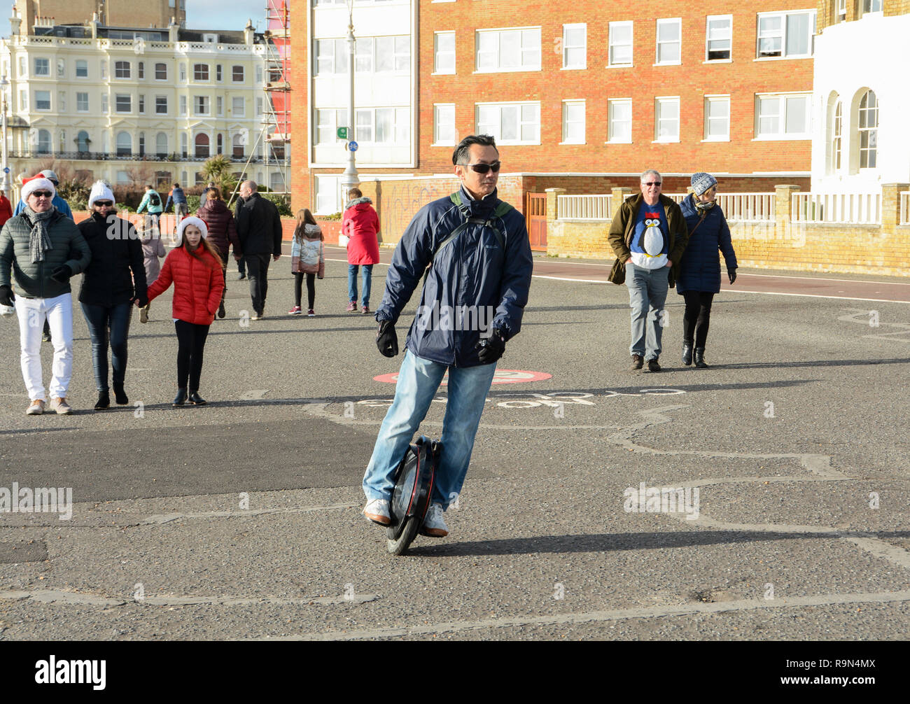 Un uomo a cavallo di un auto-bilanciamento monociclo sul lungomare di Brighton, East Sussex, England, Regno Unito Foto Stock