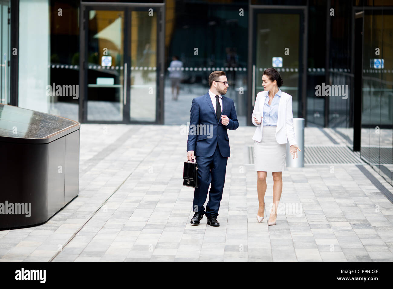 Formale di un uomo e di una donna uscendo edificio per uffici Foto Stock