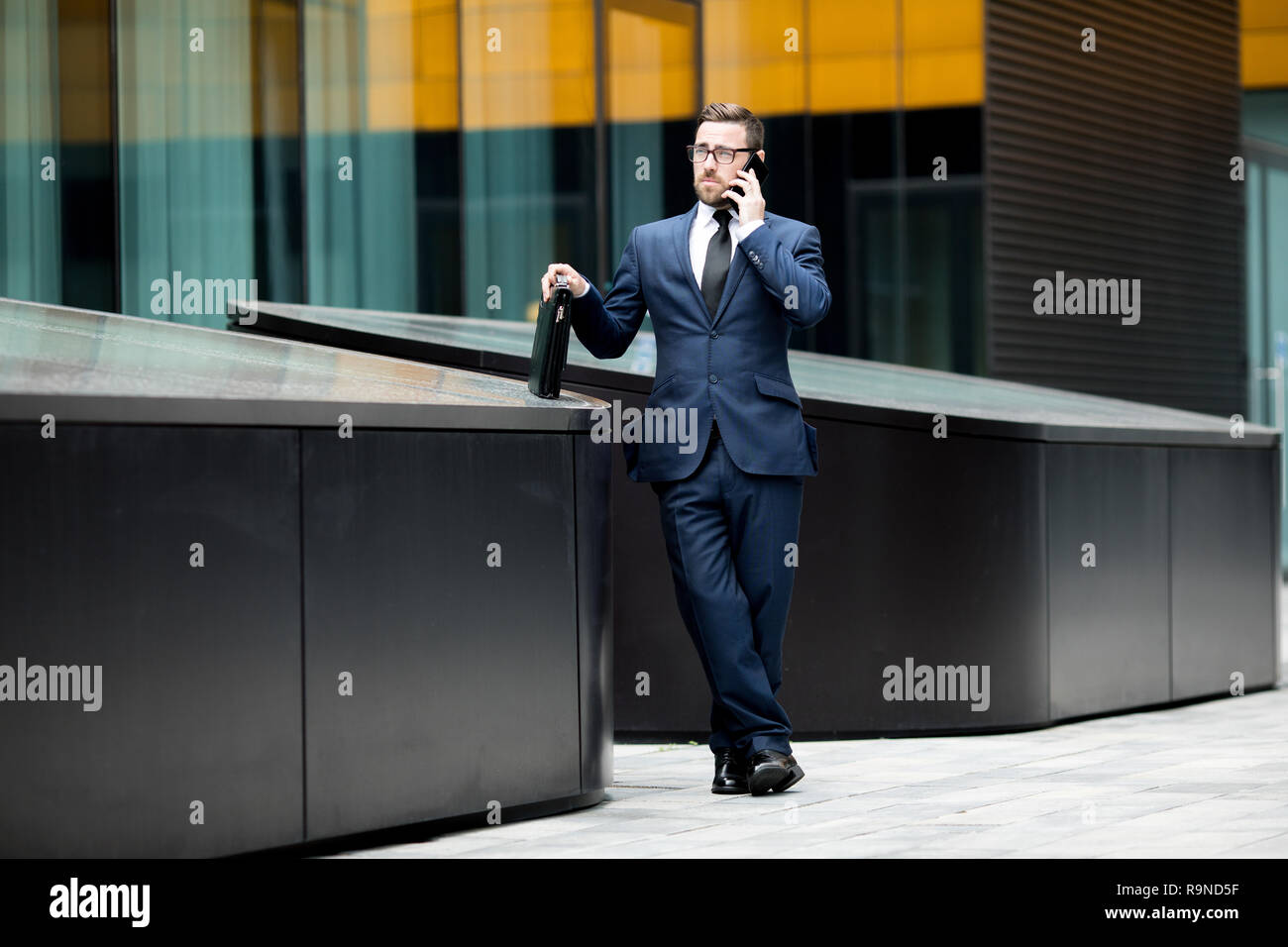 Business man parlando smartphone vicino all edificio per uffici Foto Stock