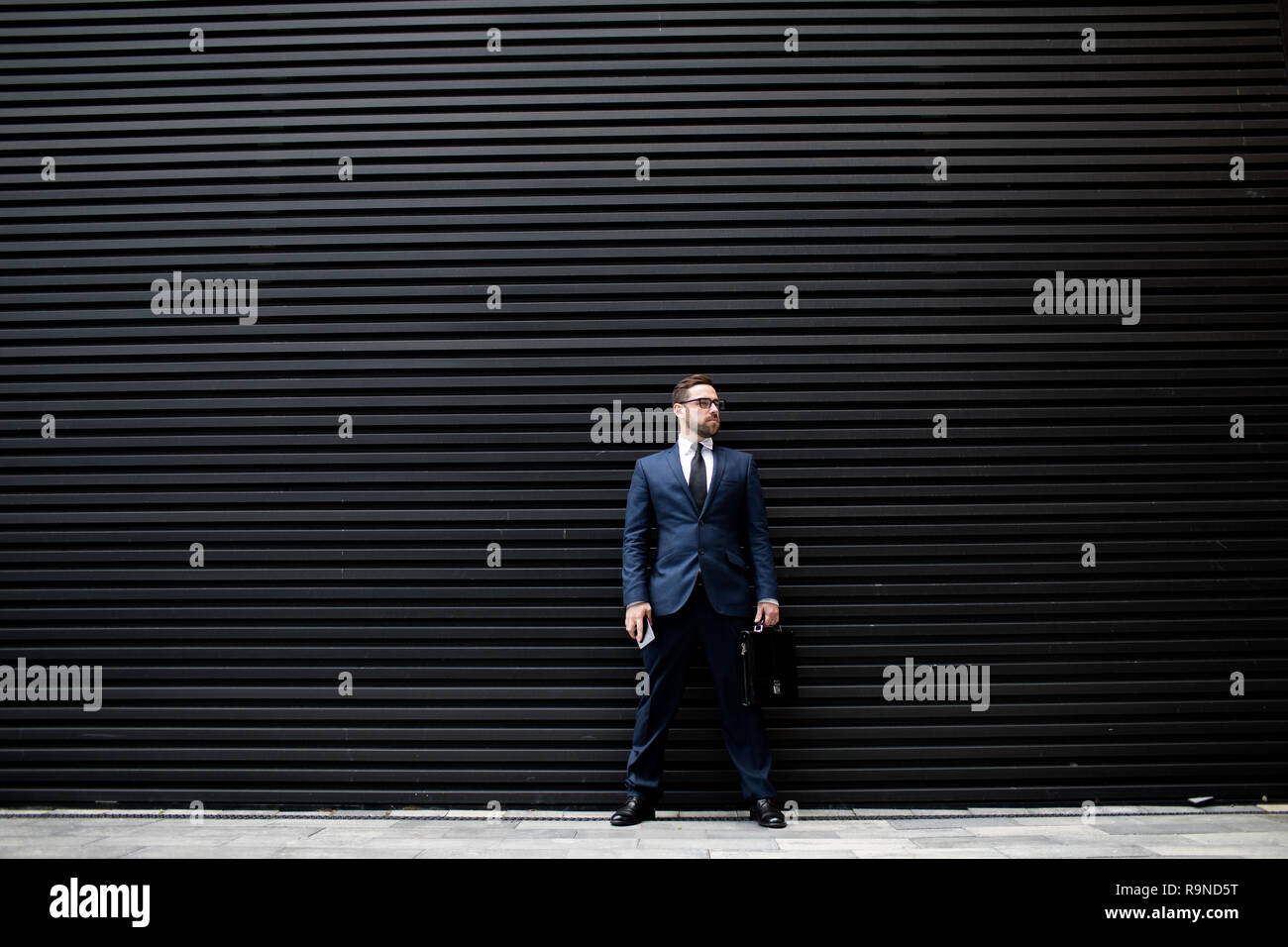 Uomo d affari con lo smartphone e valigetta Foto Stock