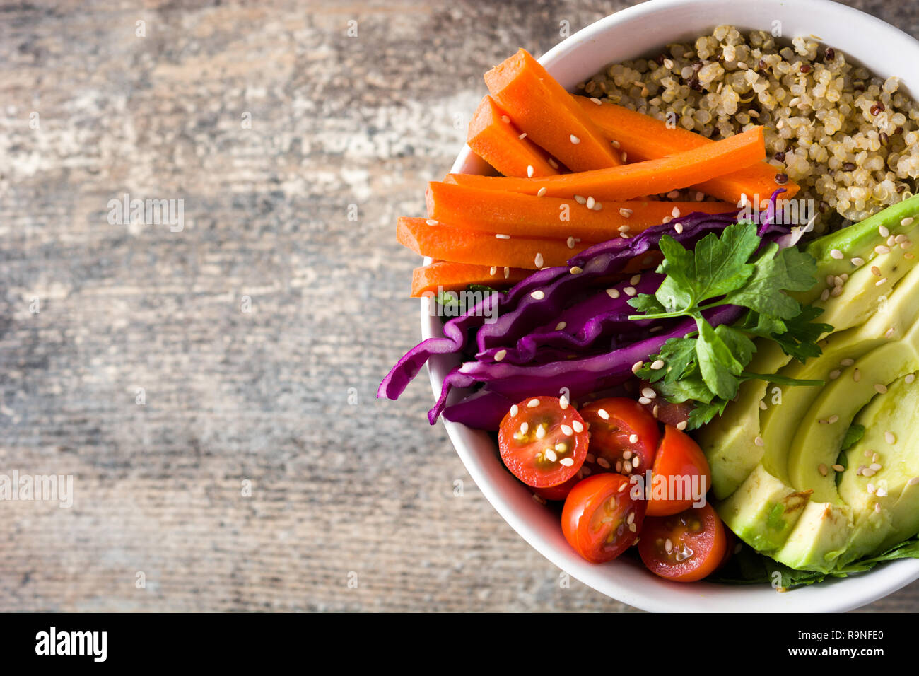 Buddha vegano ciotola con fresche verdure crude e quinoa sul tavolo di legno. Vista dall'alto. Copyspace Foto Stock
