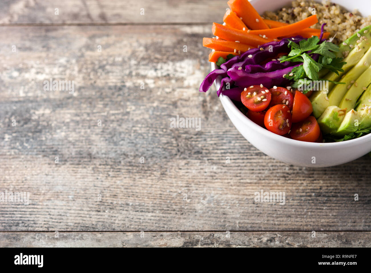 Buddha vegano ciotola con fresche verdure crude e quinoa sul tavolo di legno. Copyspace Foto Stock