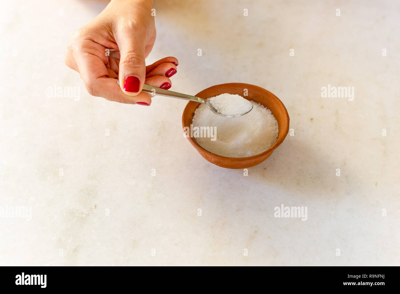 Donna mano azienda cucchiaio colmo di zucchero health care concetto. Foto Stock