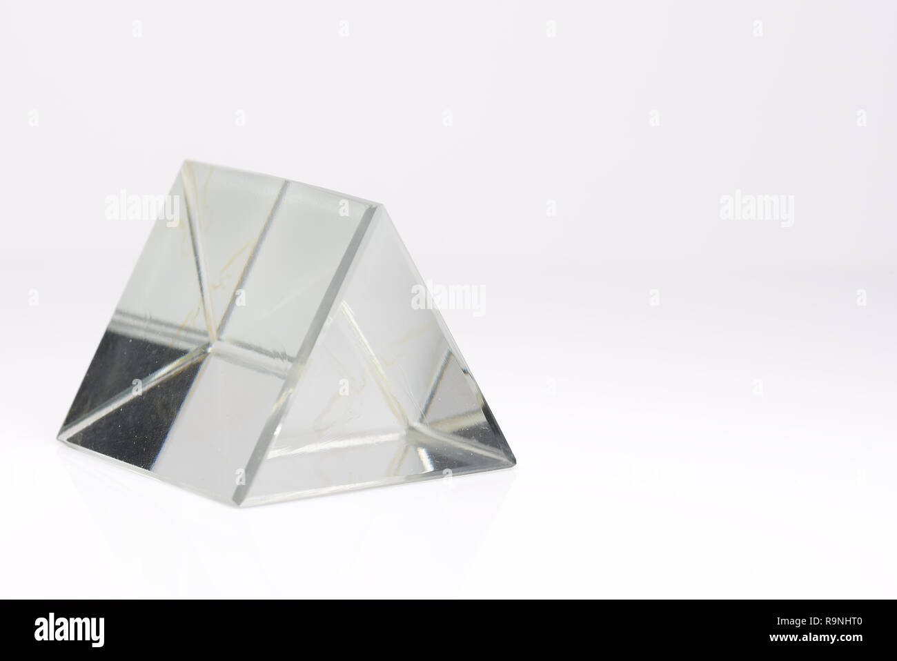 Triangolare, chiaro prisma di vetro isolato su uno sfondo bianco. Foto Stock