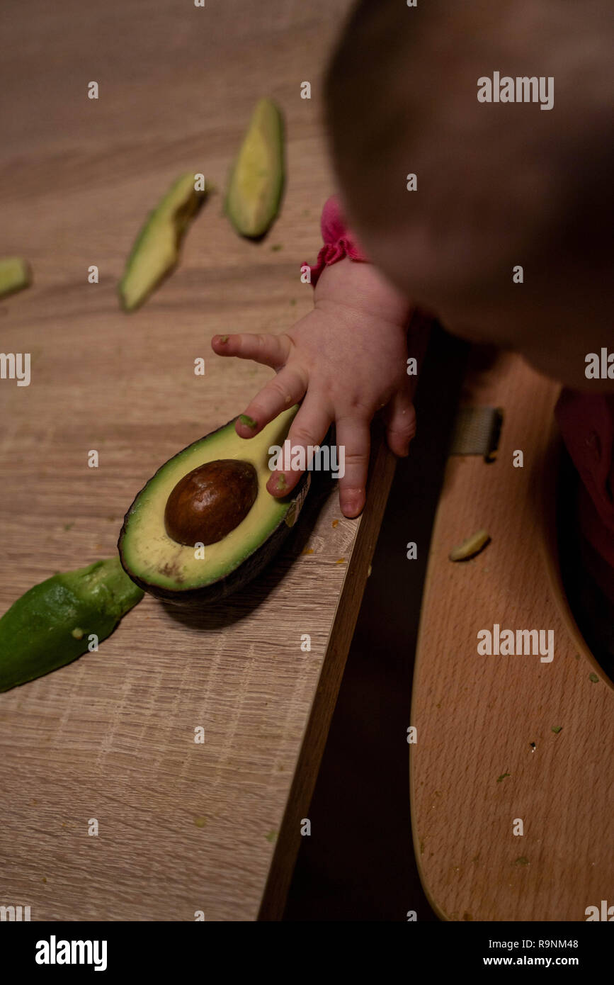 Bambini raggiunge la mano per l'avocado. Cibo sano per i bambini Foto Stock