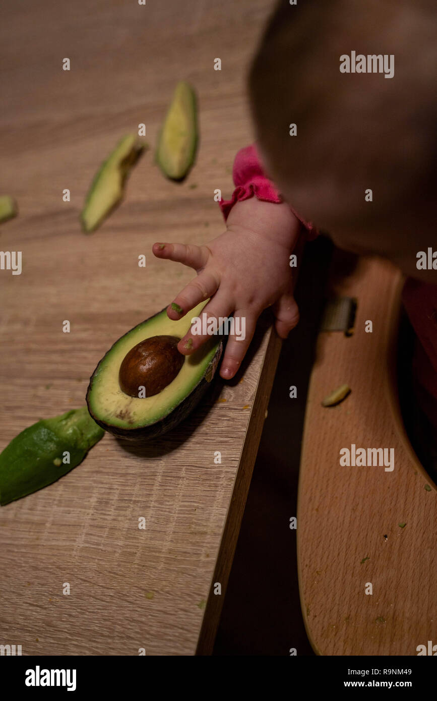 Bambini raggiunge la mano per l'avocado. Cibo sano per i bambini Foto Stock