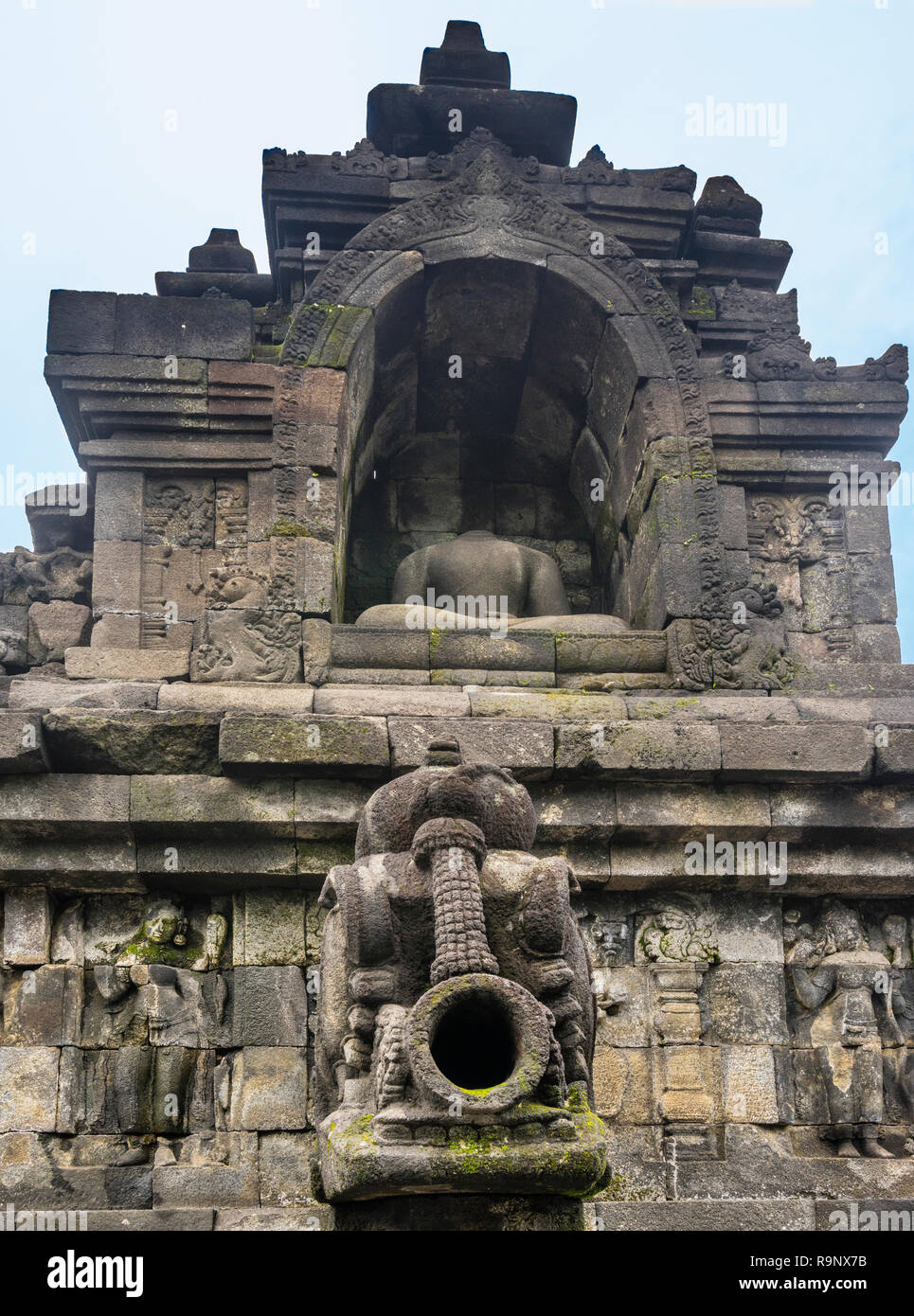 Acque piovane scolpito il tubo di lancio al di sotto di una testa di Budda seduto statua in una nicchia a IX secolo Mahayana Borobudur tempio buddista, Giava centrale, Indonesia Foto Stock