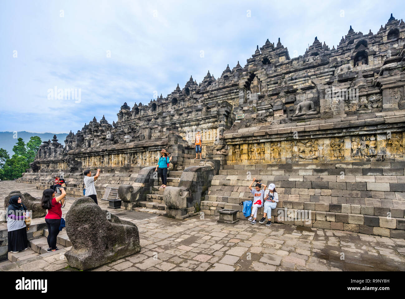 Visitatori presso la salita al mandala passo piramide del IX secolo tempio Buddhista di Borobudur e Java centrale, Indonesia Foto Stock