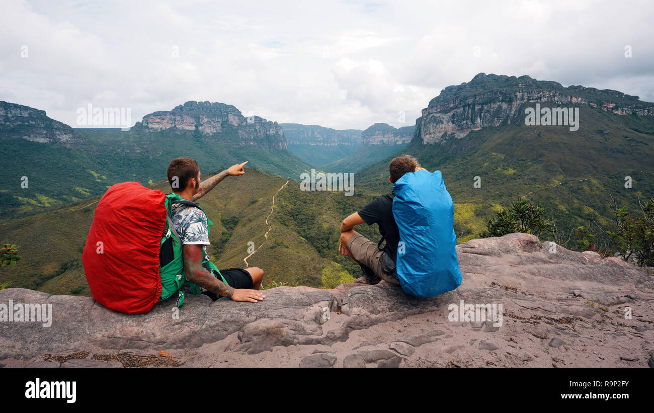 Due escursionisti seduta sul bordo e guardare oltre il paesaggio Foto Stock