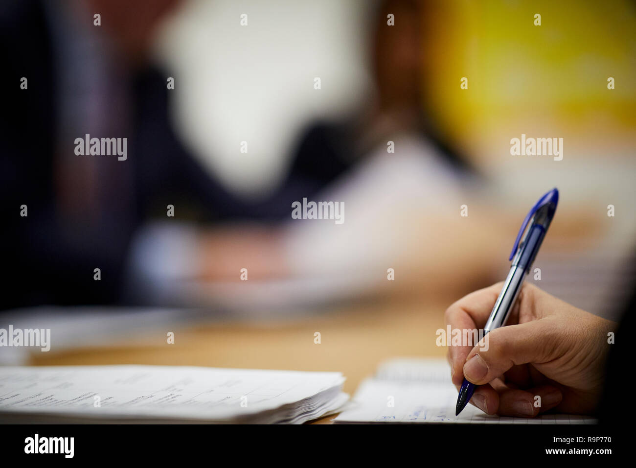 La scrittura di note in una nota scuola prenota linea Compiti di carta a una scrivania Foto Stock