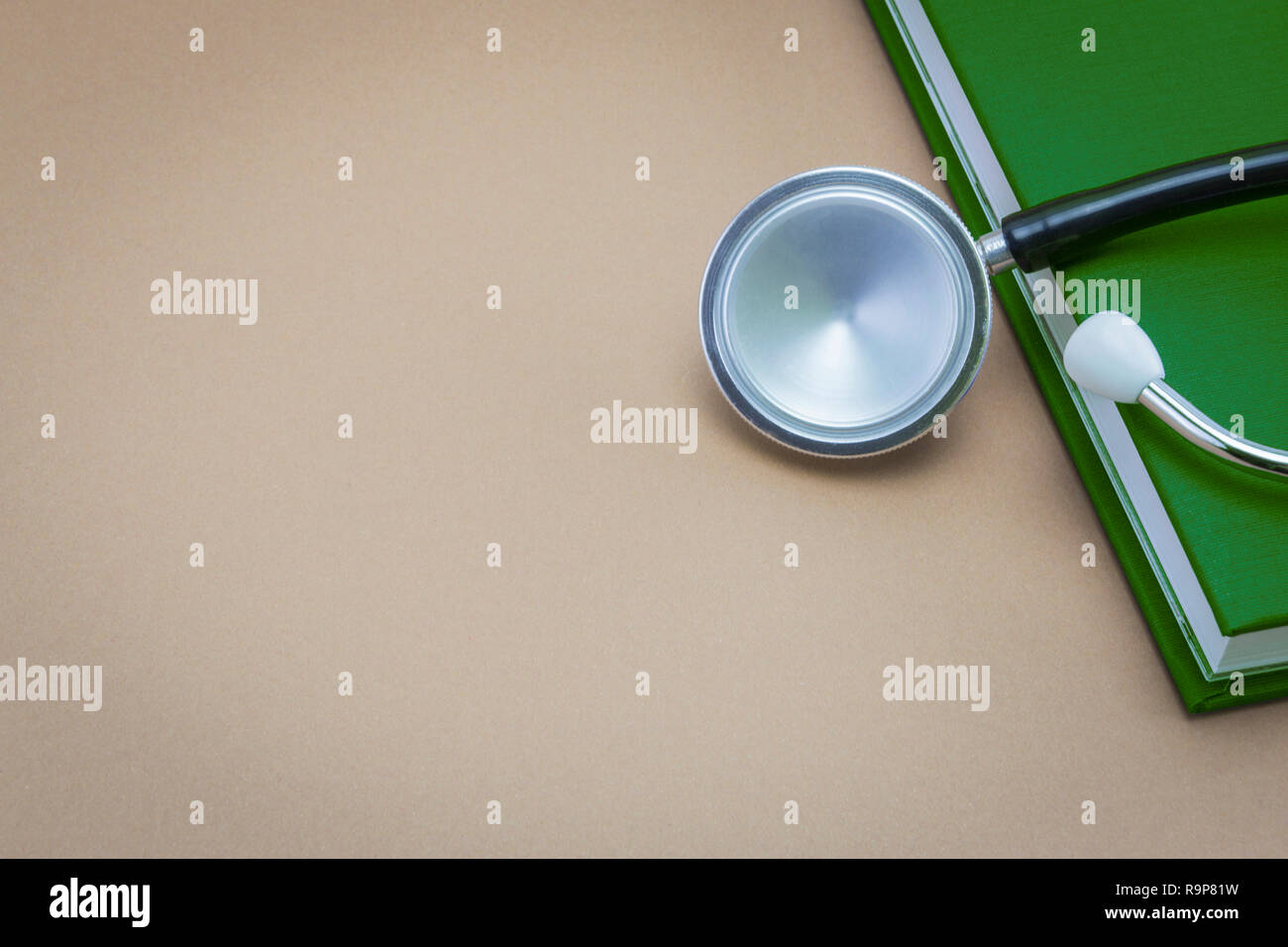 Lo stetoscopio e un libro su sfondo marrone Foto Stock