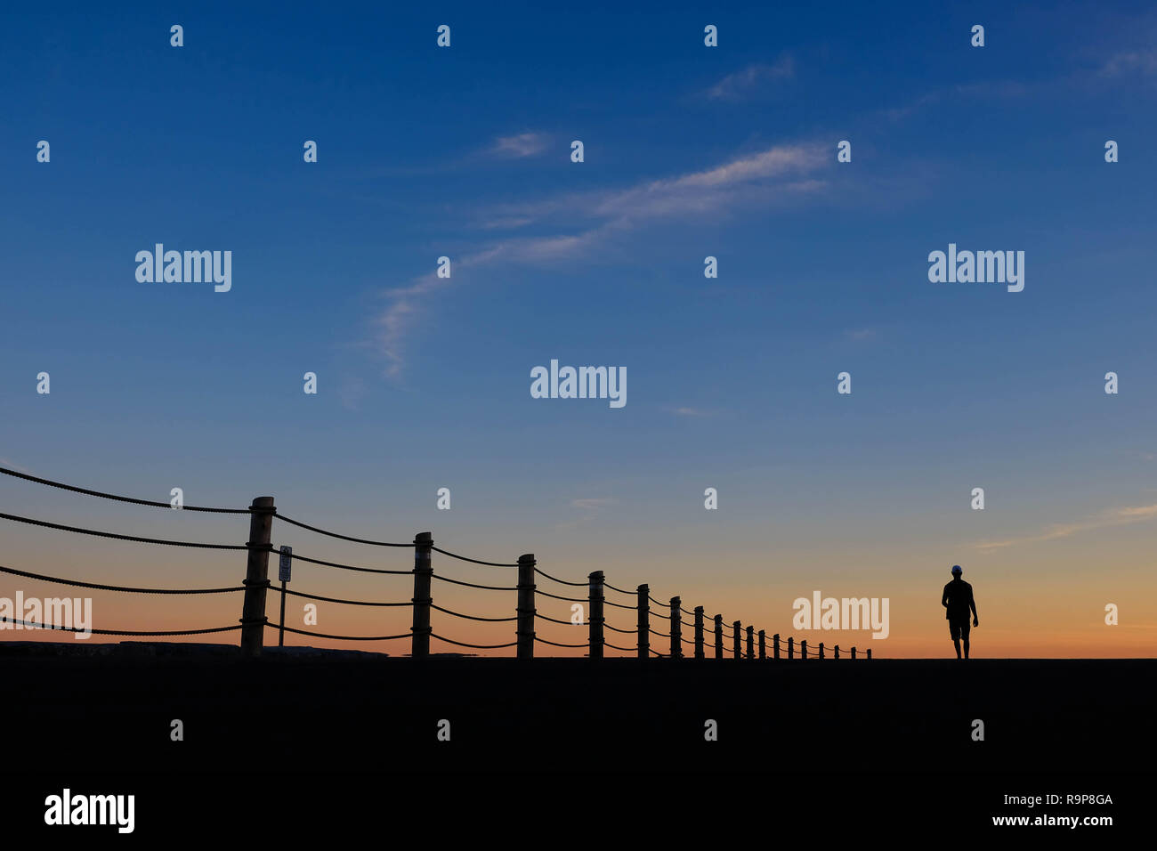 Silhouette di un uomo a camminare contro il cielo al tramonto. Foto Stock