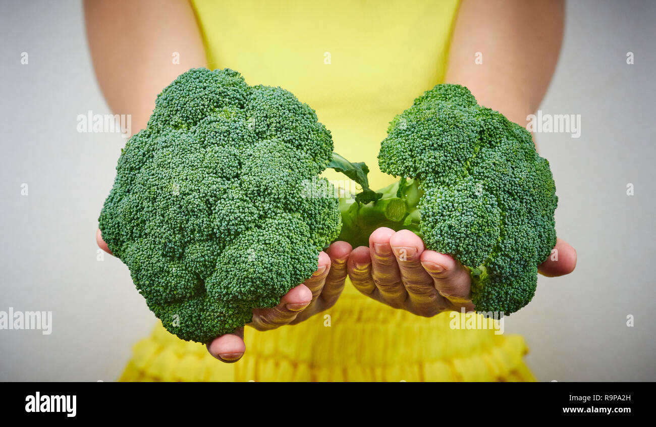 Il concetto di cibi crudi. Donna che mantiene un mazzetto di verde, materie di broccoli. close up. Foto Stock