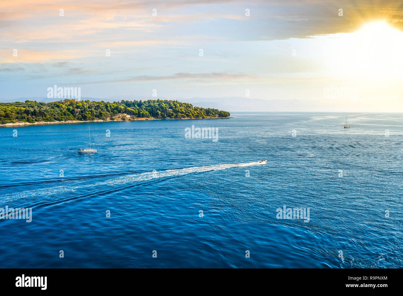 Due piccole barche a vela in mare Egeo testa verso il sole di setting battuto greco isole al largo della costa di Corfù, Grecia. Foto Stock