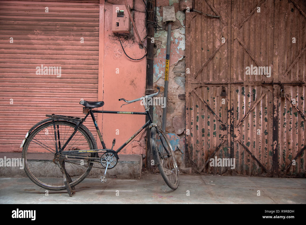La vecchia bici si è levata in piedi contro uno sfondo rosa arrugginito con navetta. Città vecchia, Jaipur, Rajasthan, INDIA. Foto Stock