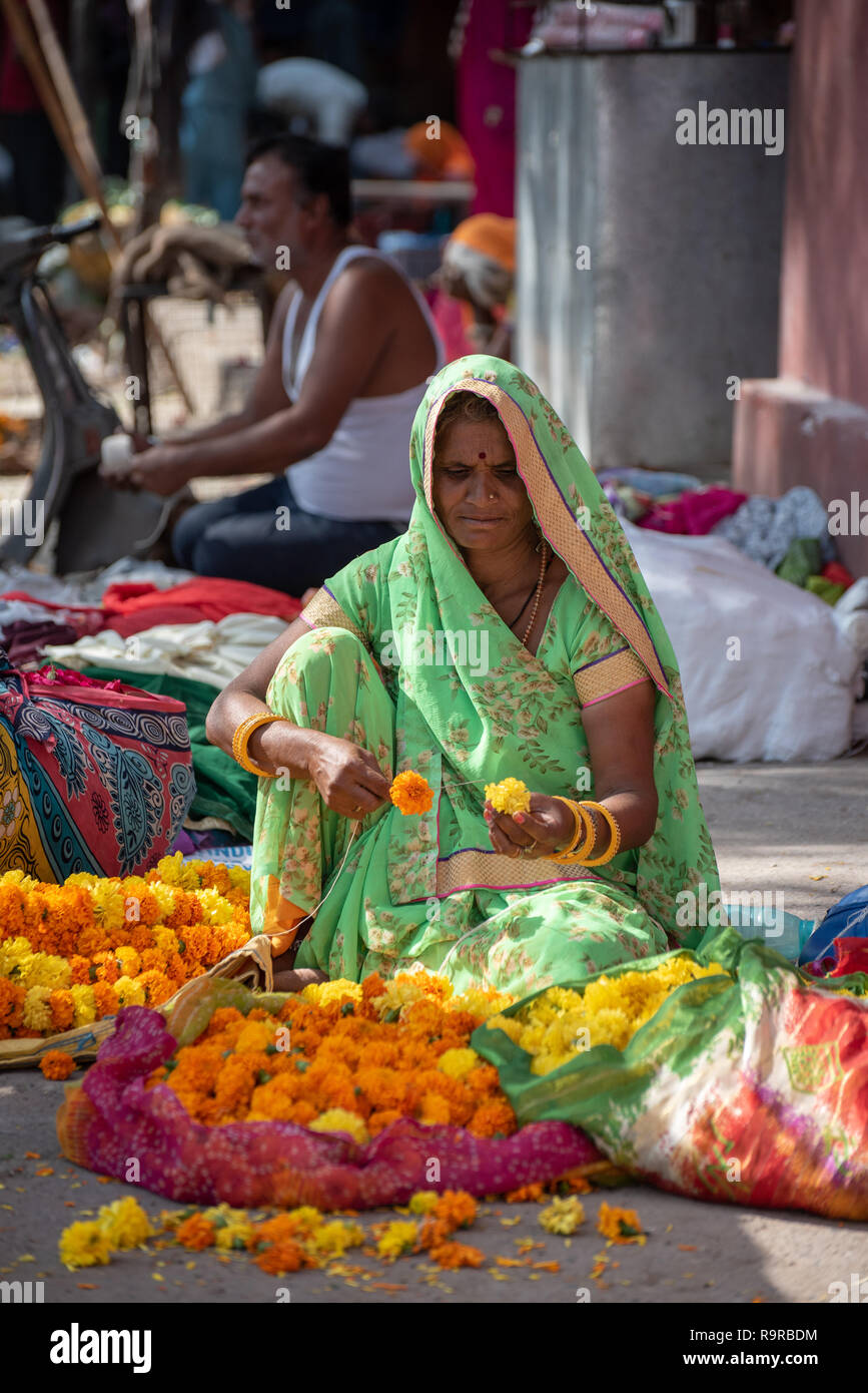 Rajasthan donna filettare un calendula garland a Jaipur il mercato dei fiori, il Rajasthan, India Foto Stock