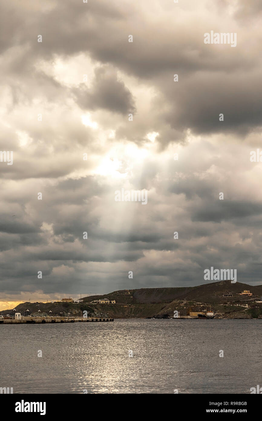 Vista di Syros litorale con un cielo nuvoloso e sunbeam. Foto Stock