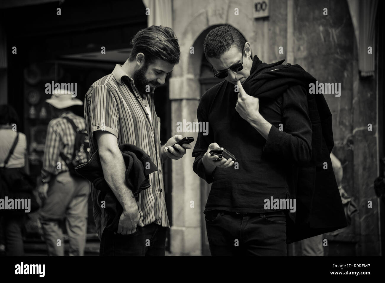 Due ragazzi guardando i telefoni cellulari in strada di Sicilia, Italia Foto Stock