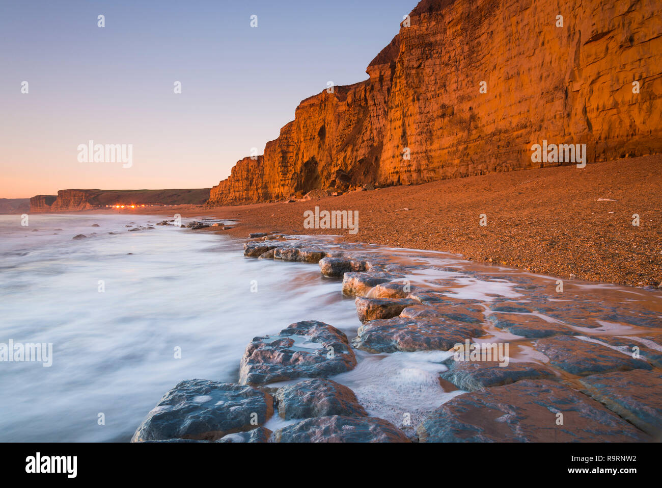 Burton Bradstock, Dorset, Regno Unito. Il 27 dicembre 2018. Regno Unito Meteo. Le scogliere di arenaria sulla spiaggia a Burton Bradstock sul Dorset Jurassic Coast glow orange al tramonto dopo un pomeriggio di chiari cieli soleggiati. Credito Foto: Graham Hunt/Alamy Live News Foto Stock