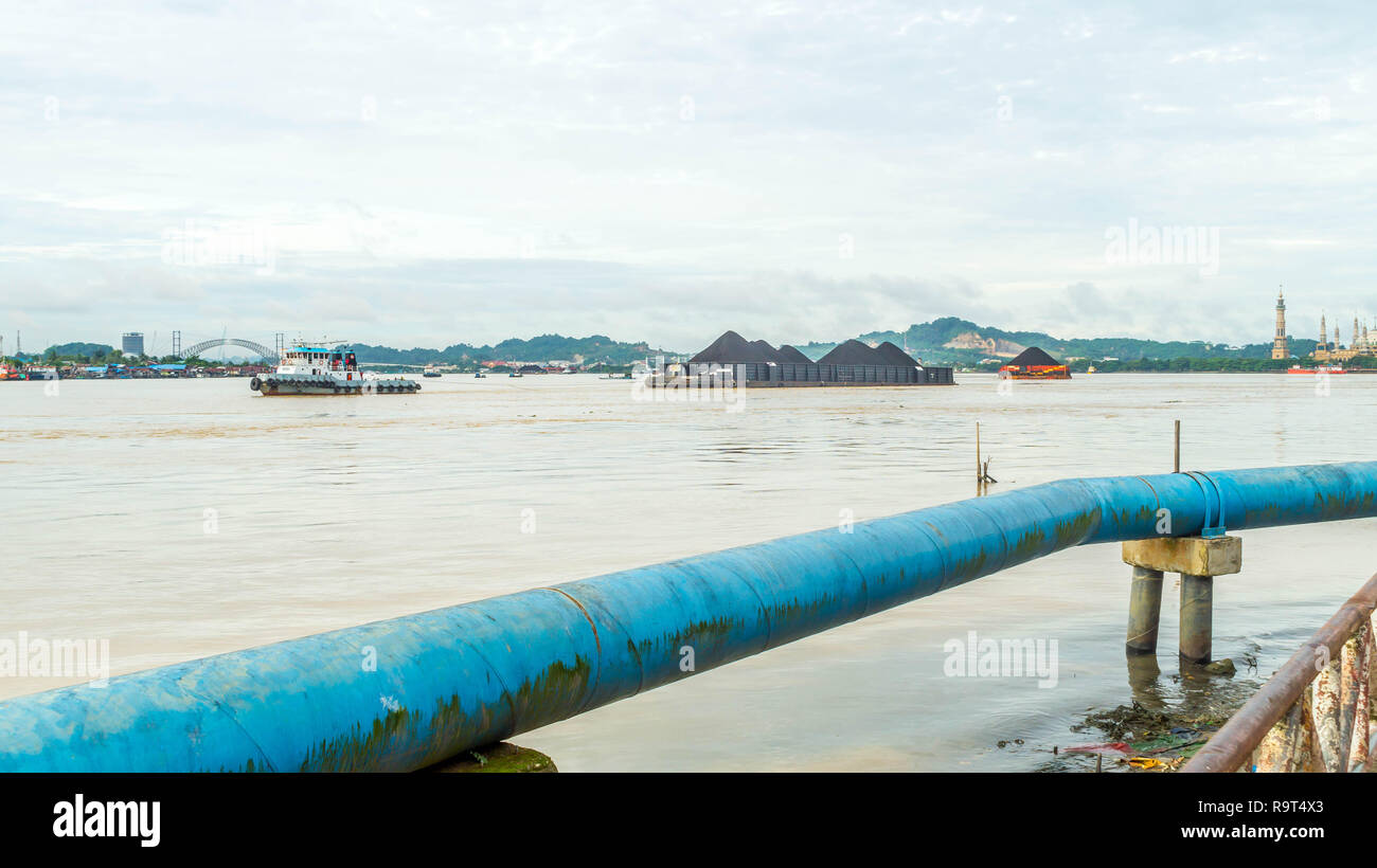 Tirare in barca chiatta piena di carbone di crociera sul fiume Mahakam davanti di Samarinda Grande moschea Foto Stock