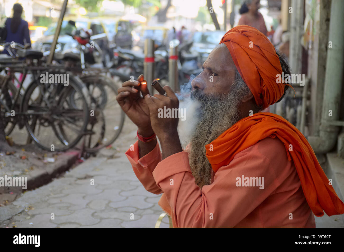 Un sadhu o uomo santo, un seguace del dio indù Shiva, fumare hashish o cannabis in una strada in Mumbai, India, la cannabis è associato con Shiva Foto Stock