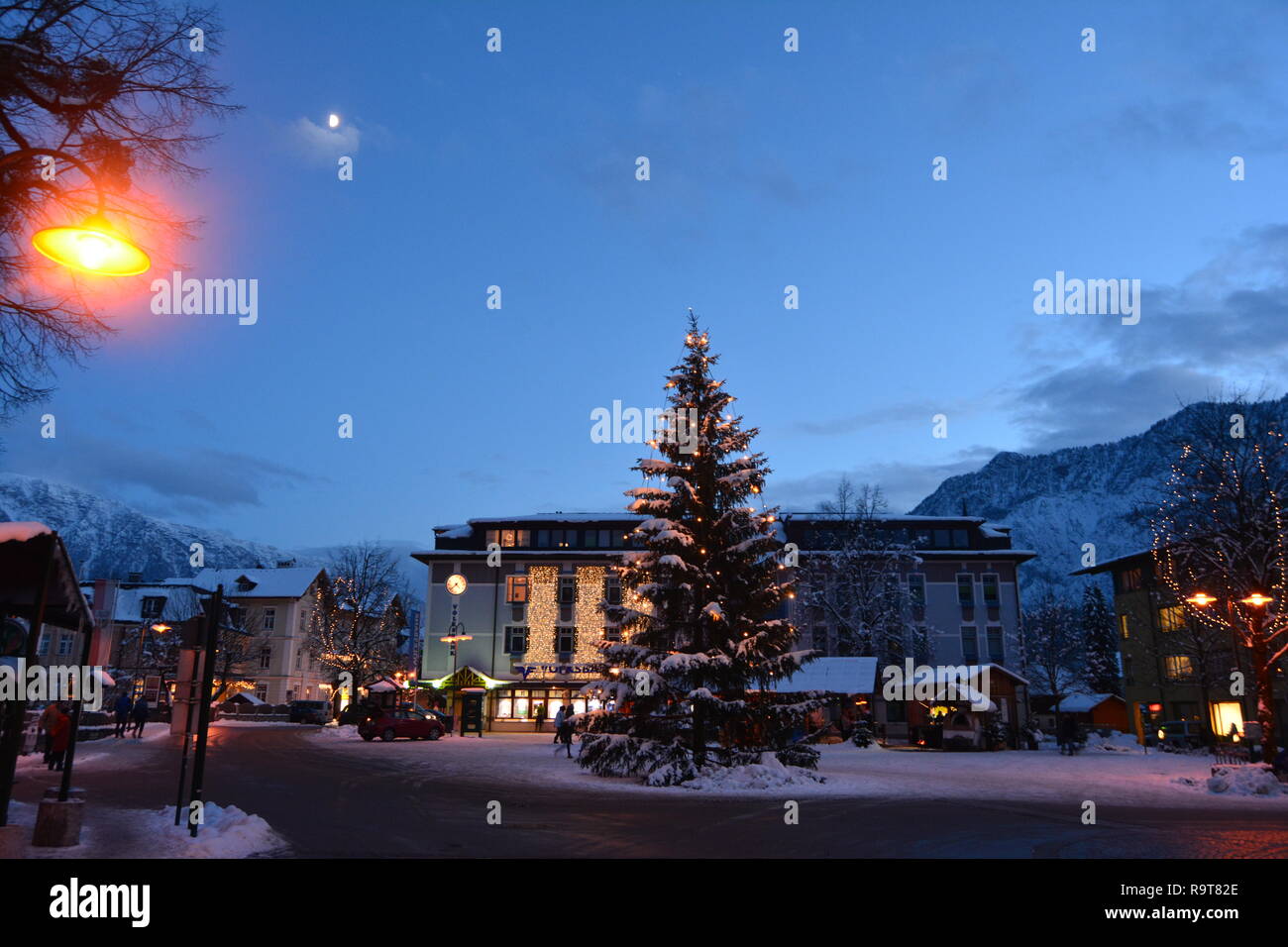 Bad Goisern, Hallstatt, Austria. Vista notturna dell albero di Natale nel centro. Montagne innevate e la luna in background. Foto Stock