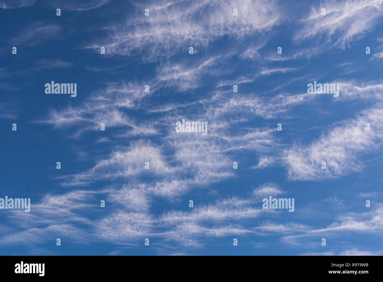 Nuvole bianche di aspetto filamentoso, contro un luminoso cielo blu Foto Stock