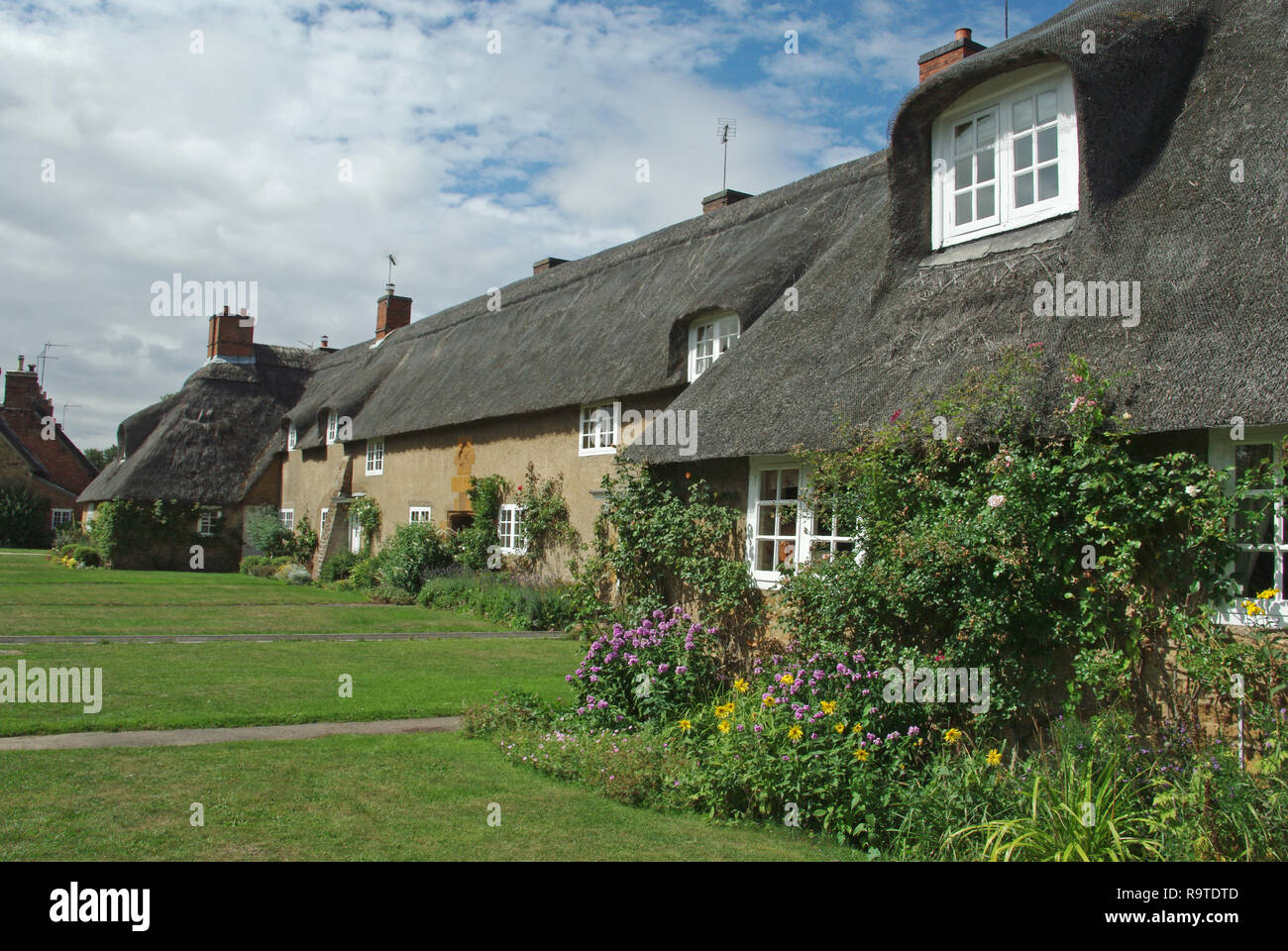Una pittoresca terrazza del cottage con il tetto di paglia nel villaggio di Ashby St partitari, Northamptonshire, Regno Unito; costruita nei primi anni del XX secolo da Sir Edwin Lutyens. Foto Stock