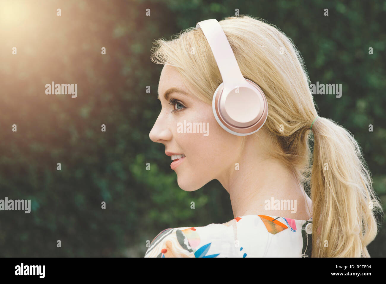 Un bianco millenario femmina ha un ispirazione e felice momento durante l'ascolto di musica con cuffie rosa Foto Stock