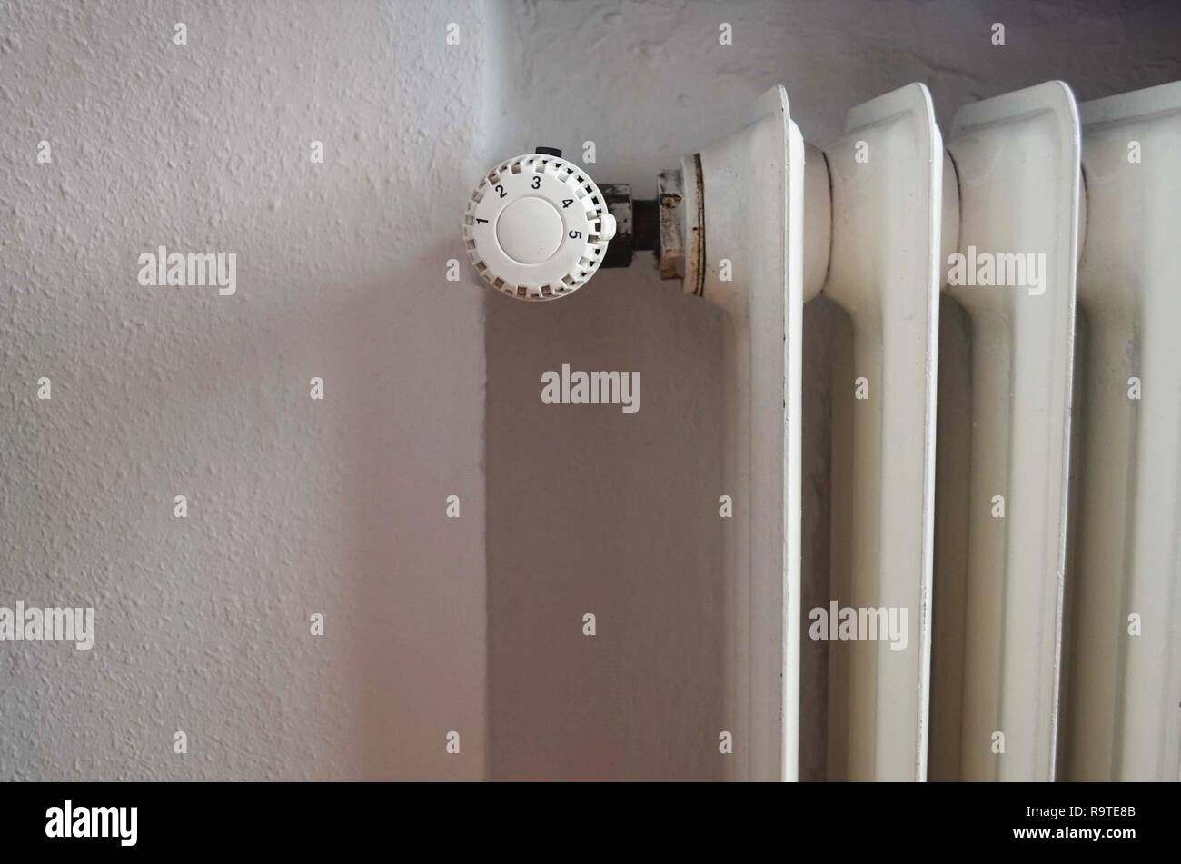 Rusty vecchio radiatore accanto a una parete bianca in una casa mobile in una proprietà Foto Stock