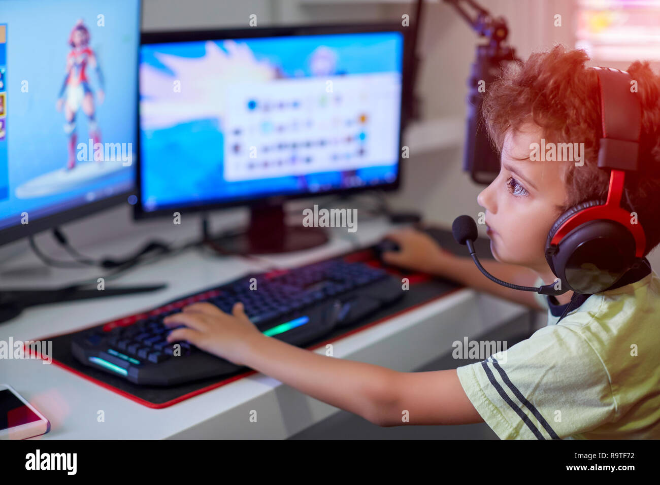 Felice ragazzo seduto alla sua scrivania con un computer portatile Foto Stock