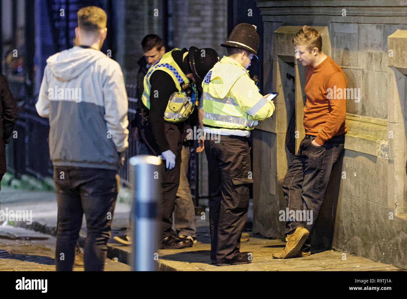 Nella foto: un uomo è parlata da funzionari di polizia. Venerdì 14 Dicembre 2018 Re: festaioli nel vento Street, Swansea, Wales, Regno Unito. Foto Stock