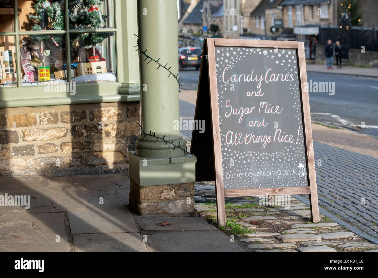 Lavagna di Natale al di fuori del negozio di dolci Burford a Natale. Burford, Cotswolds, Oxfordshire, Inghilterra Foto Stock