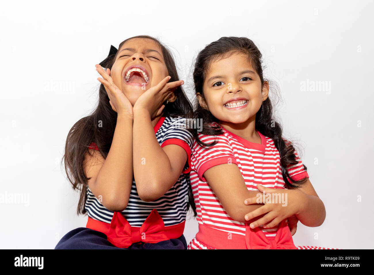 Carino sorelle con abiti a strisce di ridere Foto Stock
