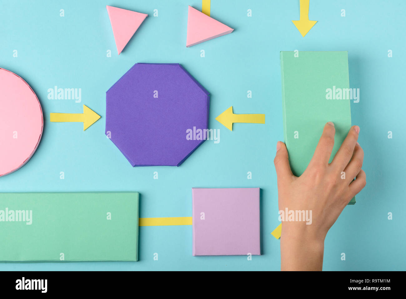 Diagramma di flusso colore modello di carta. La donna il collegamento di diversi blocchi con le frecce, rendendo un algoritmo. Foto Stock