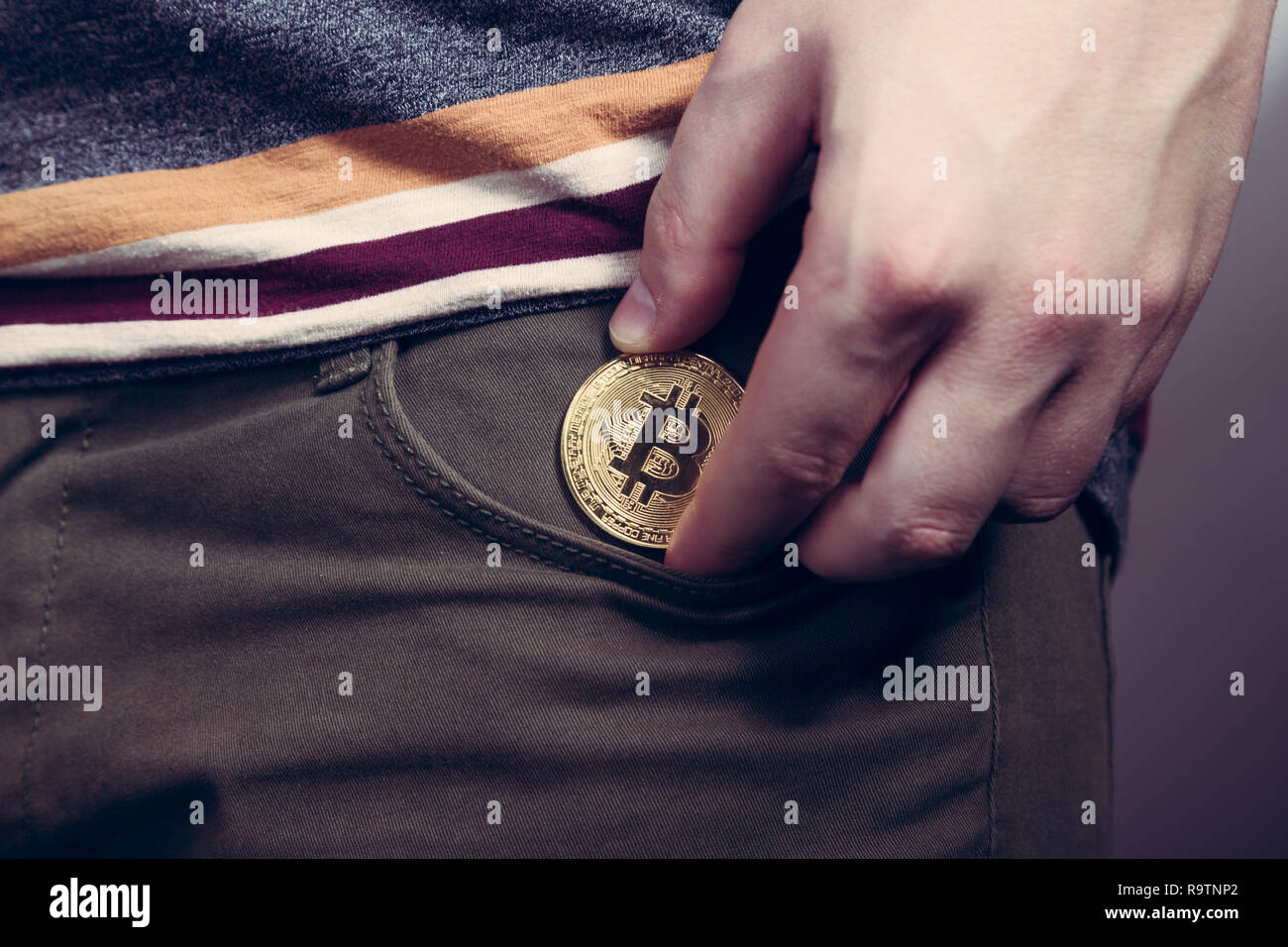 Mettere bitcoin cryptocurrency moneta nella tasca come investimento Foto Stock