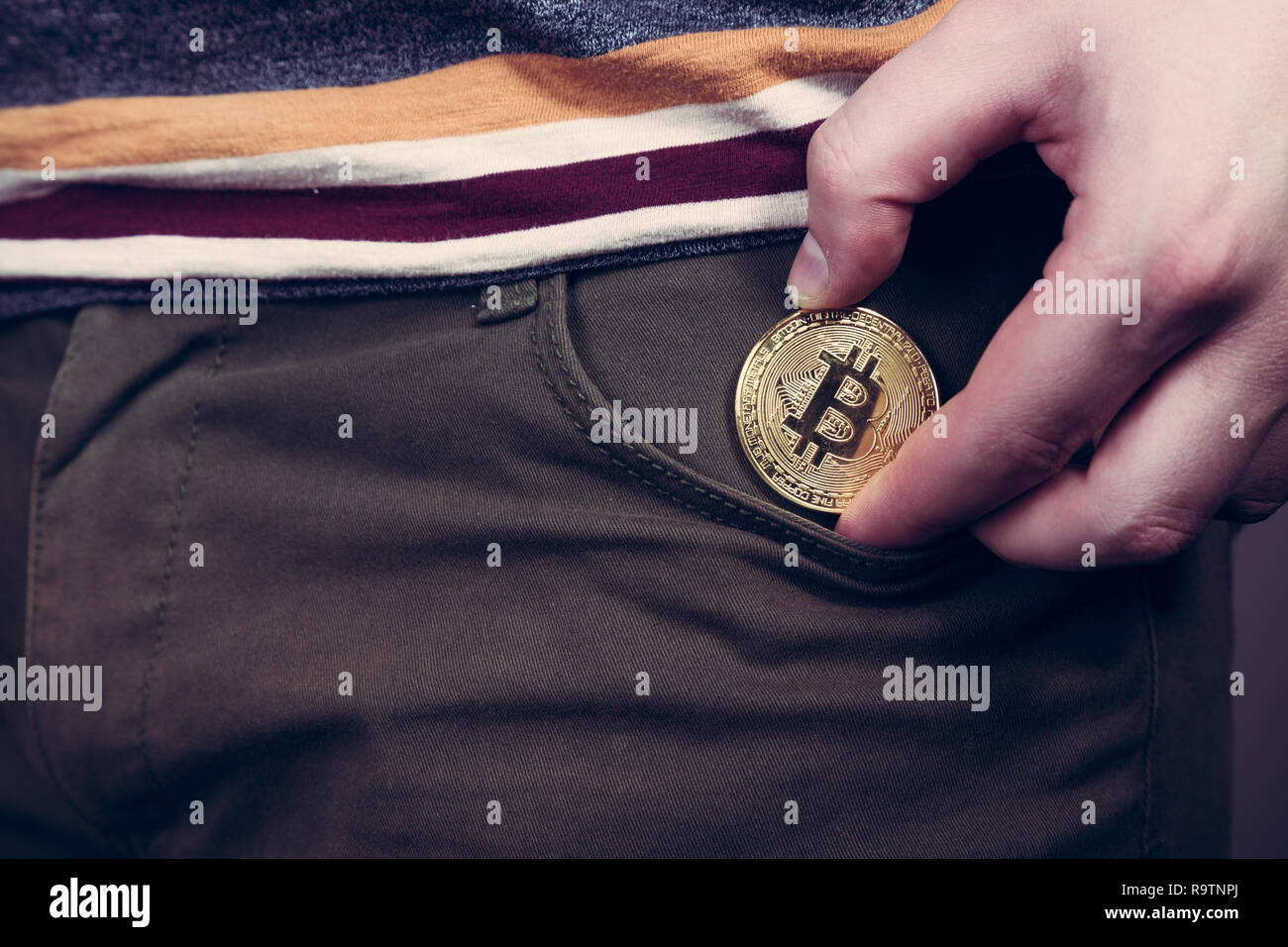 Mettere bitcoin cryptocurrency moneta nella tasca come investimento Foto Stock