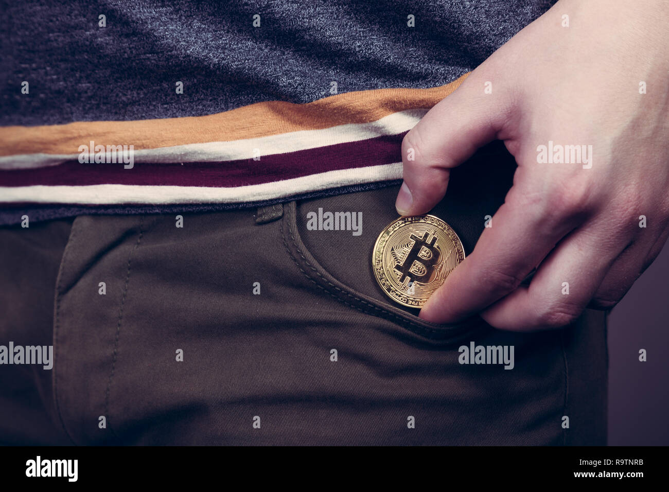Mettere bitcoin cryptocurrency moneta nella tasca come investimento Foto Stock