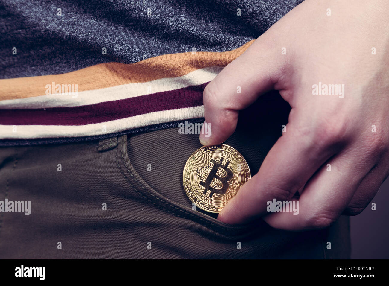 Mettere bitcoin cryptocurrency moneta nella tasca come investimento Foto Stock