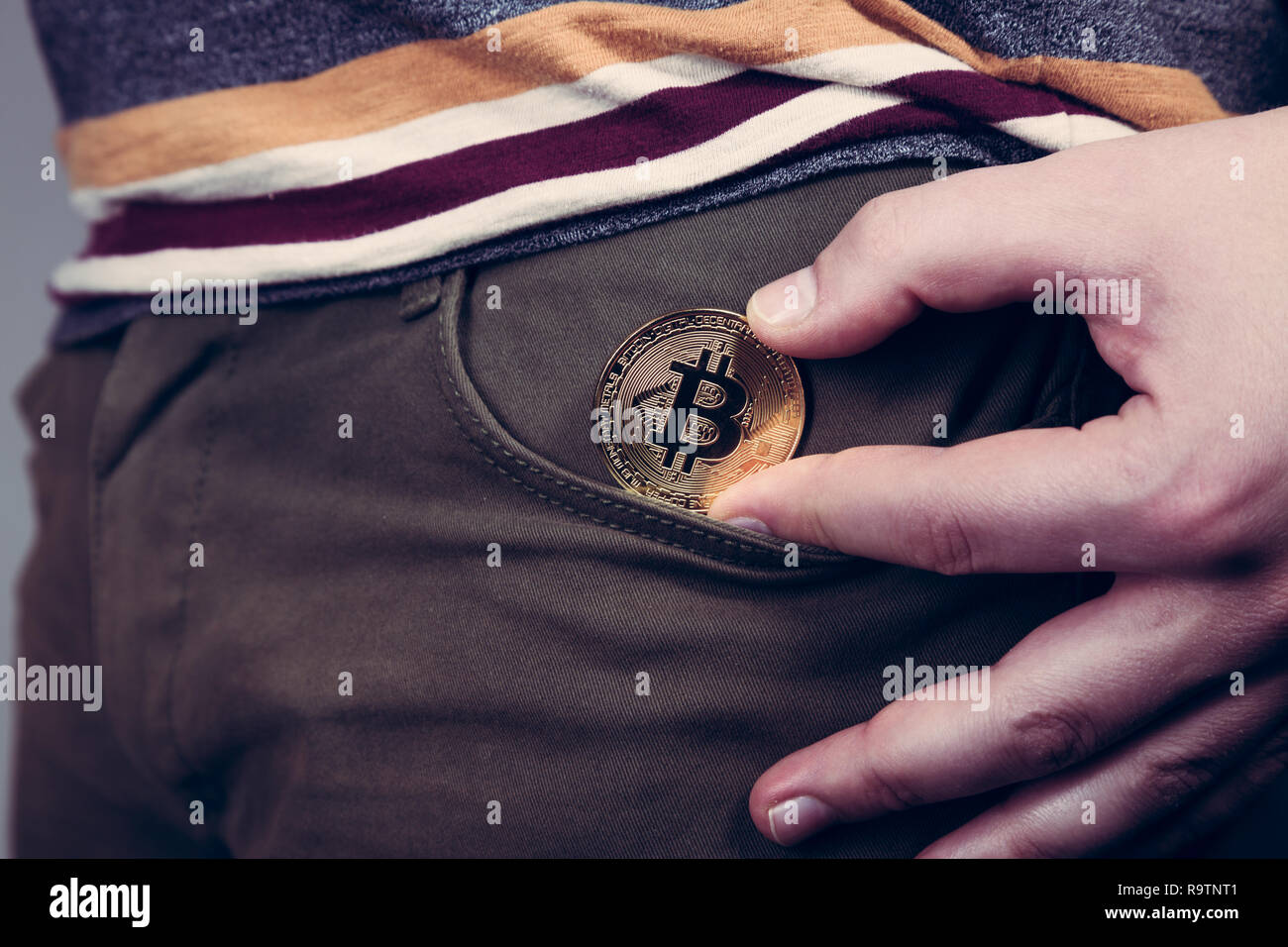 Mettere bitcoin cryptocurrency moneta nella tasca come investimento Foto Stock
