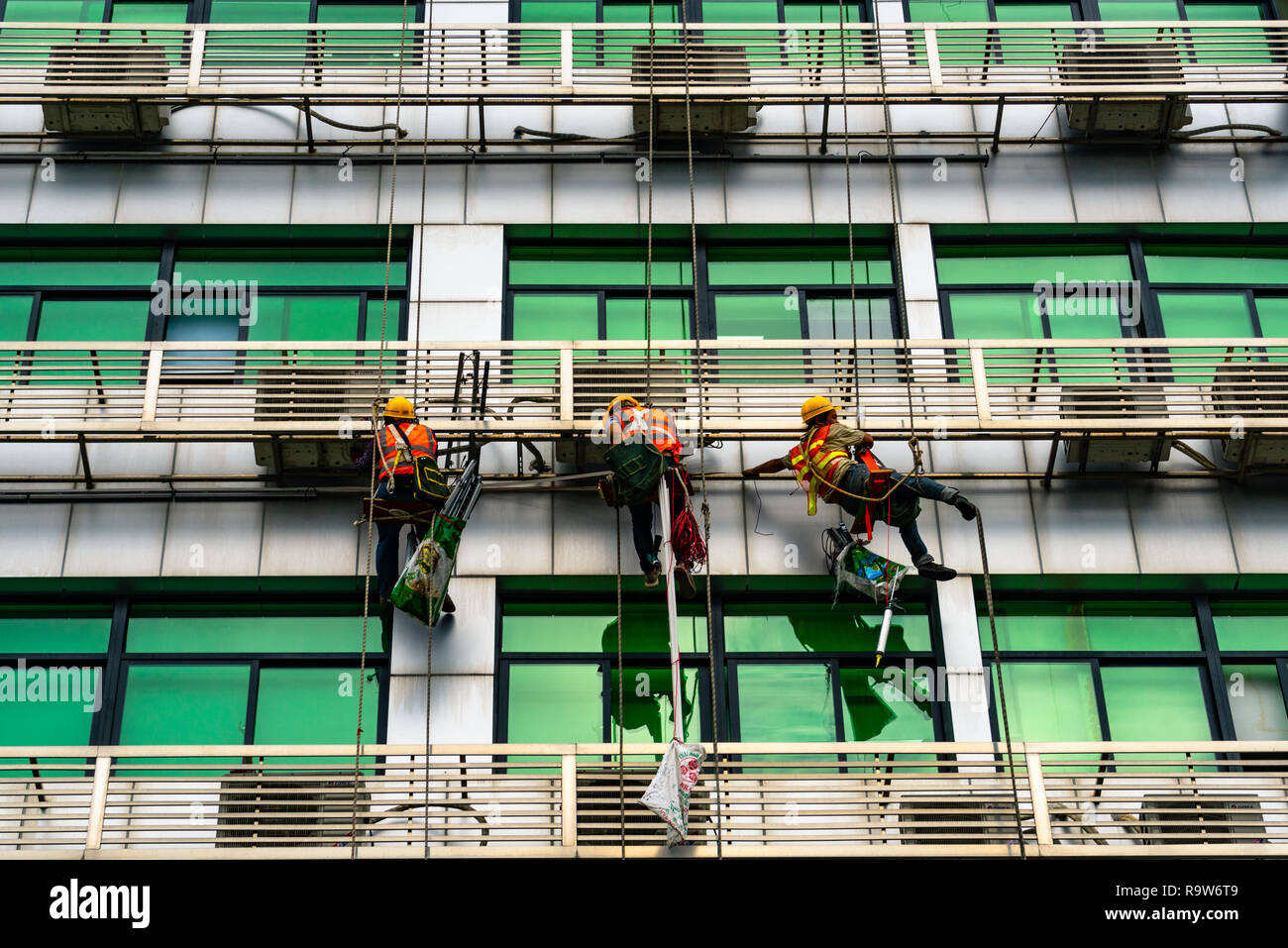 Occupazione: repairmen sospesa mediante cavi all esterno dell'edificio in Shenzhen, Cina Foto Stock