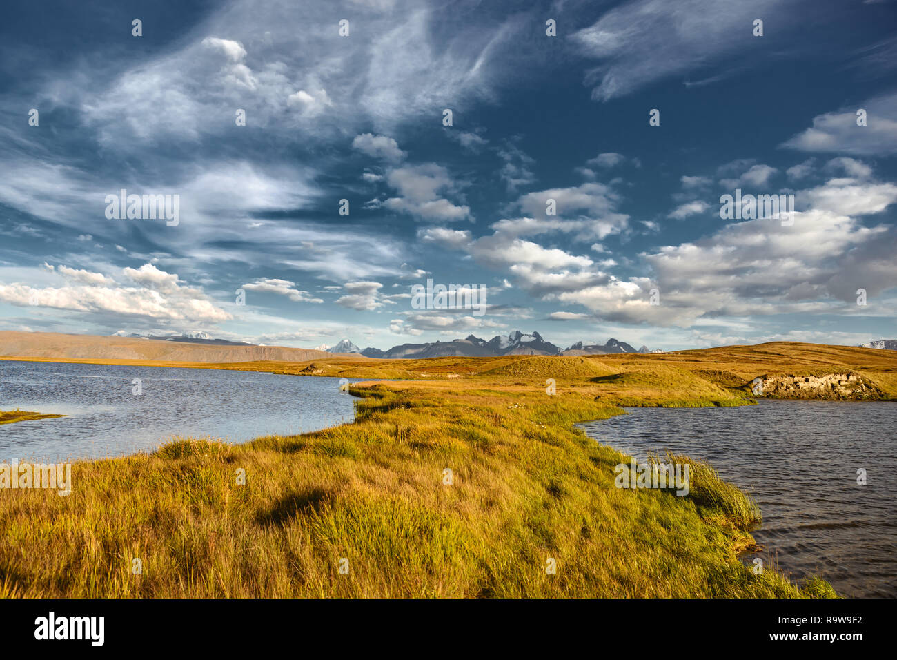 Paesaggio sereno con superficie di acqua, montagne innevate e giallo Erba. Montagne di Altai, Siberia, Russia Foto Stock