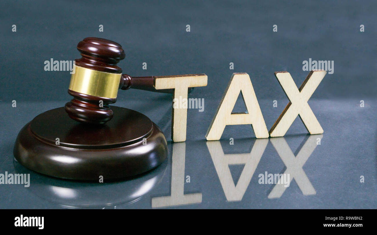 Diritto fiscale concetto. Tassa di parola con martello e il denaro sul tavolo. Foto Stock