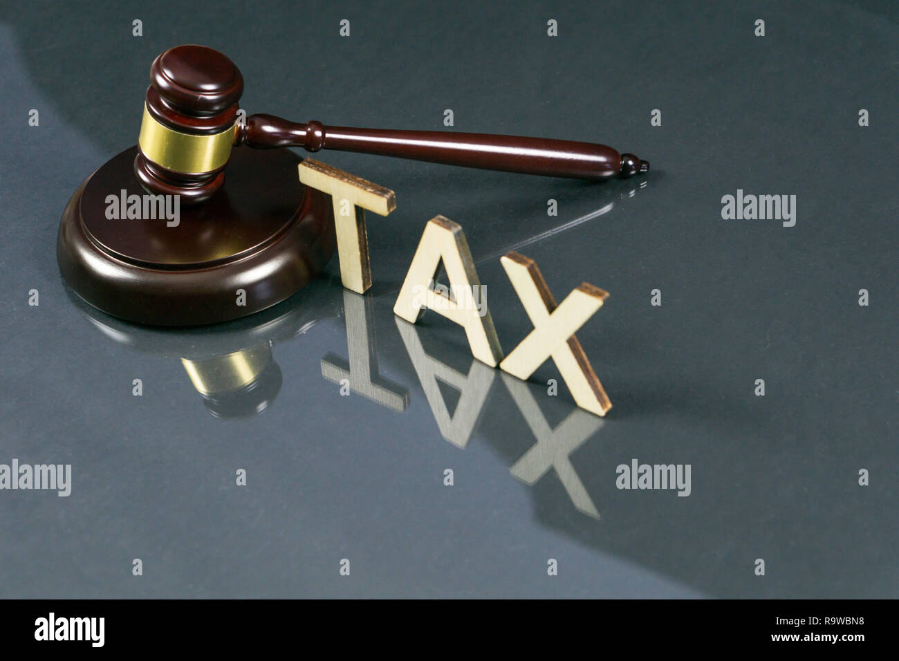 Diritto fiscale concetto. Tassa di parola con martello e il denaro sul tavolo. Foto Stock