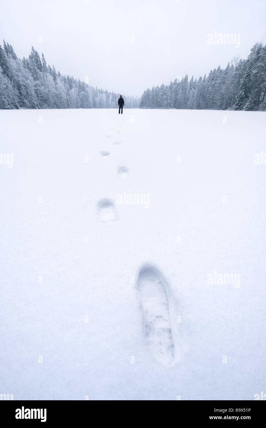 Paesaggio invernale con footprint e lonely man a umore il giorno in Finlandia. Foto Stock