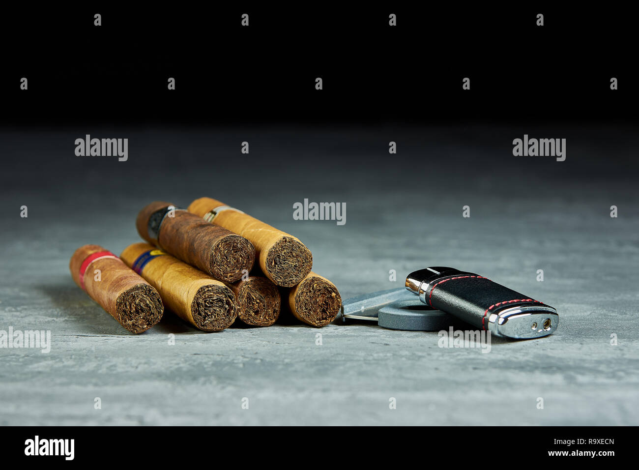Sei sigari cubani su un tavolo di pietra con un accendino e la taglierina Foto Stock